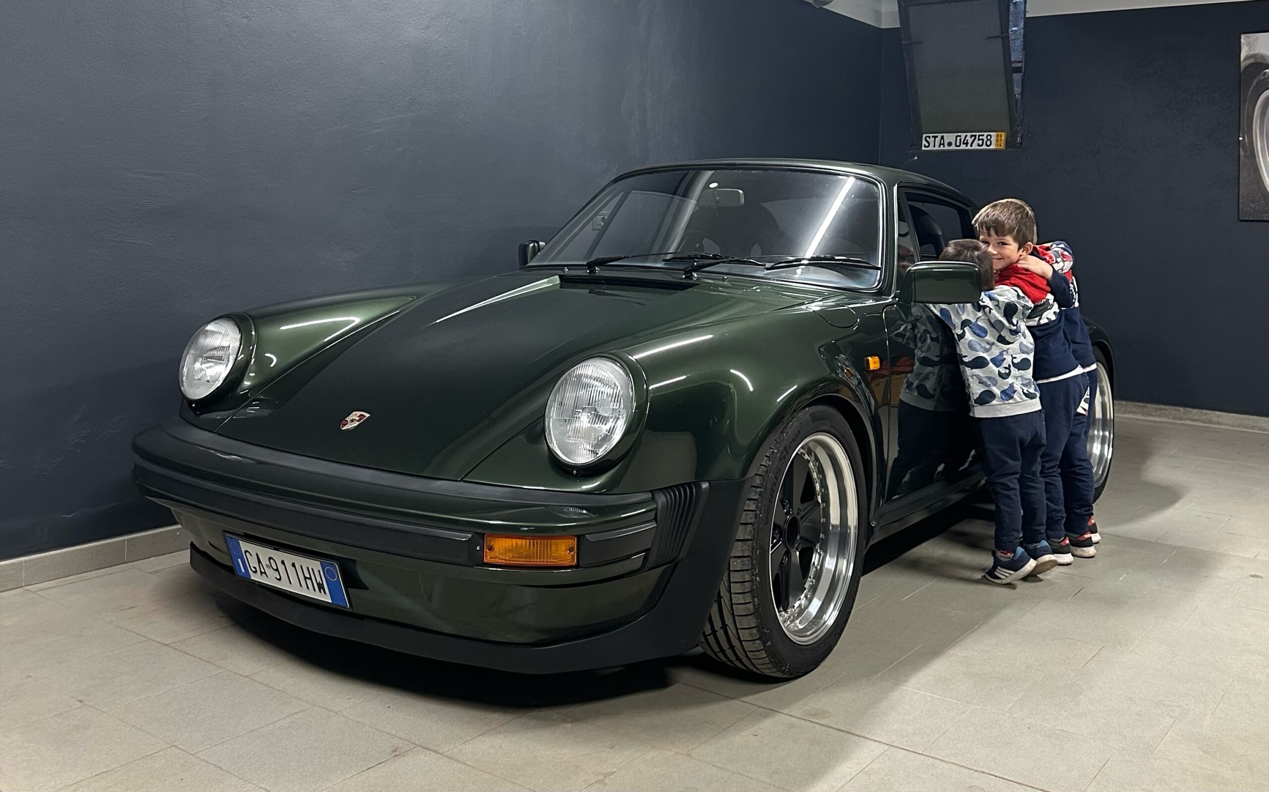 Two boys admire a green classic Porsche 911