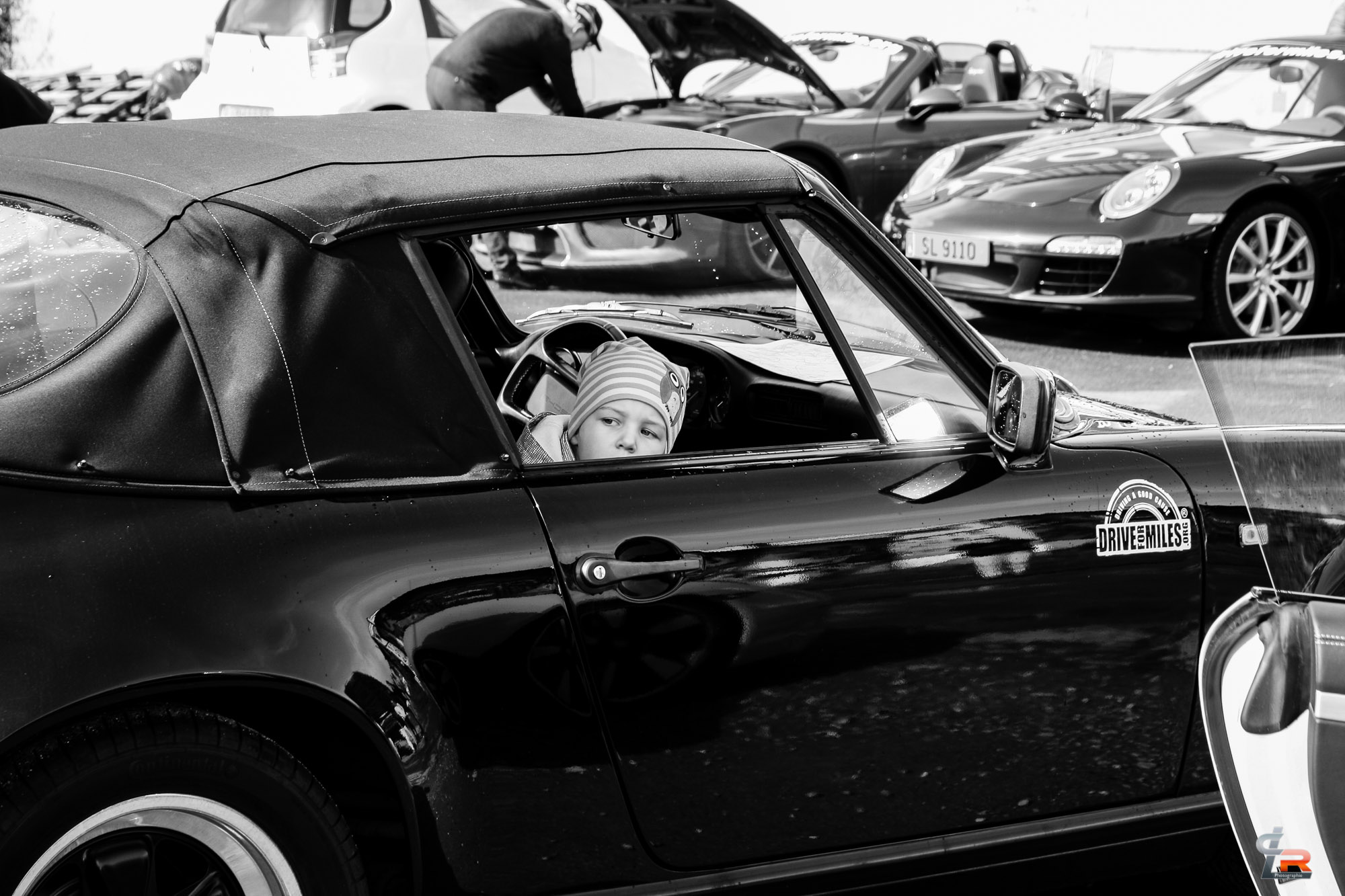 A child in a black classic convertible (black and white)