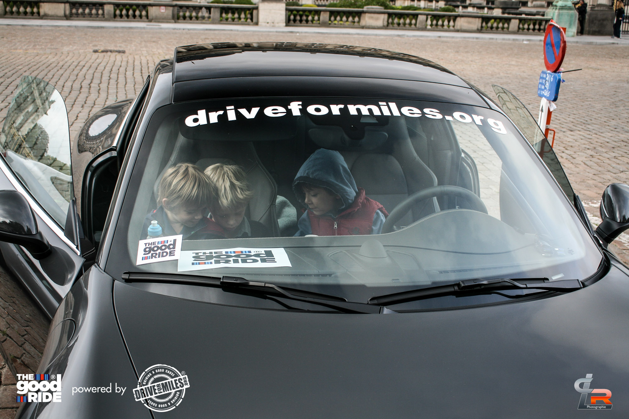 Children sitting in a Drive for Miles Porsche