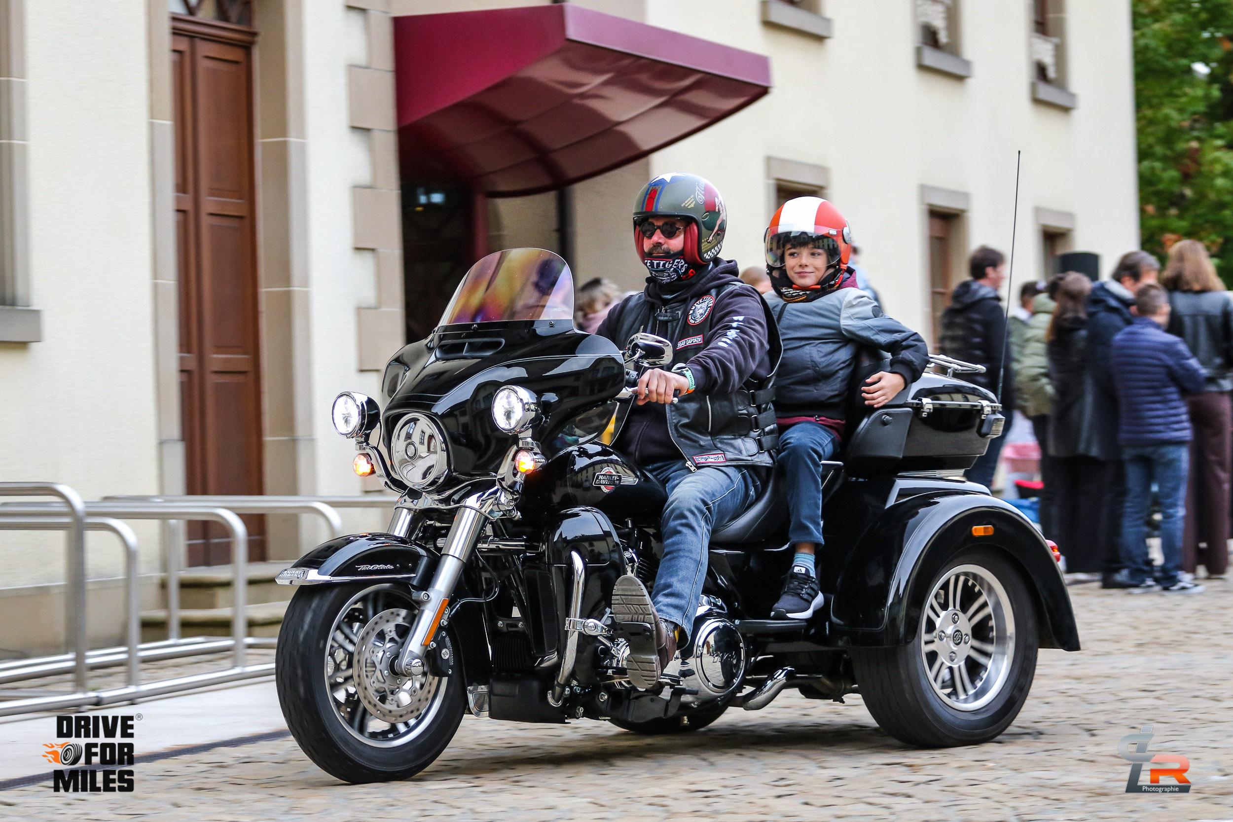 A rider and a child passenger on a motorbike trike